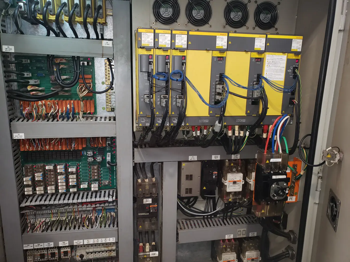 VA Electronic Solutions engineer's work inside a Fanuc CNC control cabinet — servo amplifiers, relay boards and terminal wiring for machine monitoring retrofit